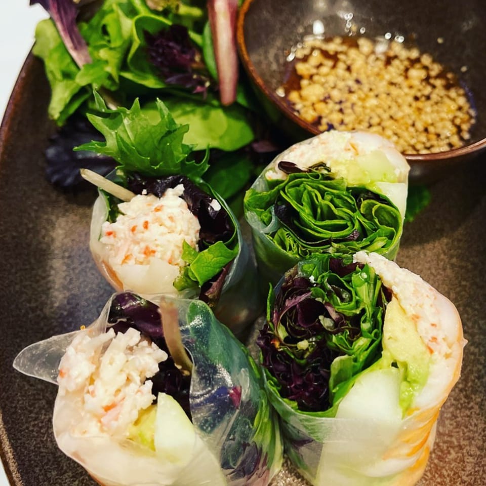 Four fresh Thai spring rolls with crab, avocado, and lettuce, served with a side salad and dipping sauce.