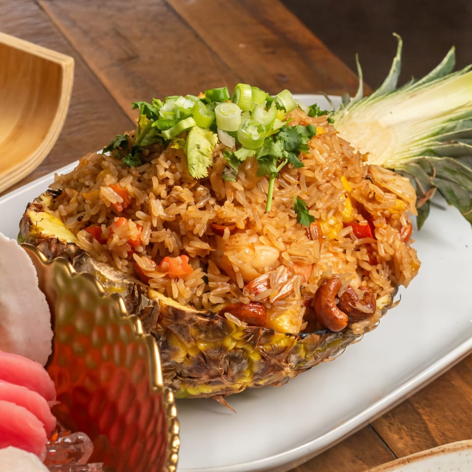 Thai pineapple fried rice with shrimp, cashews, and vegetables, garnished with green onions and cilantro.